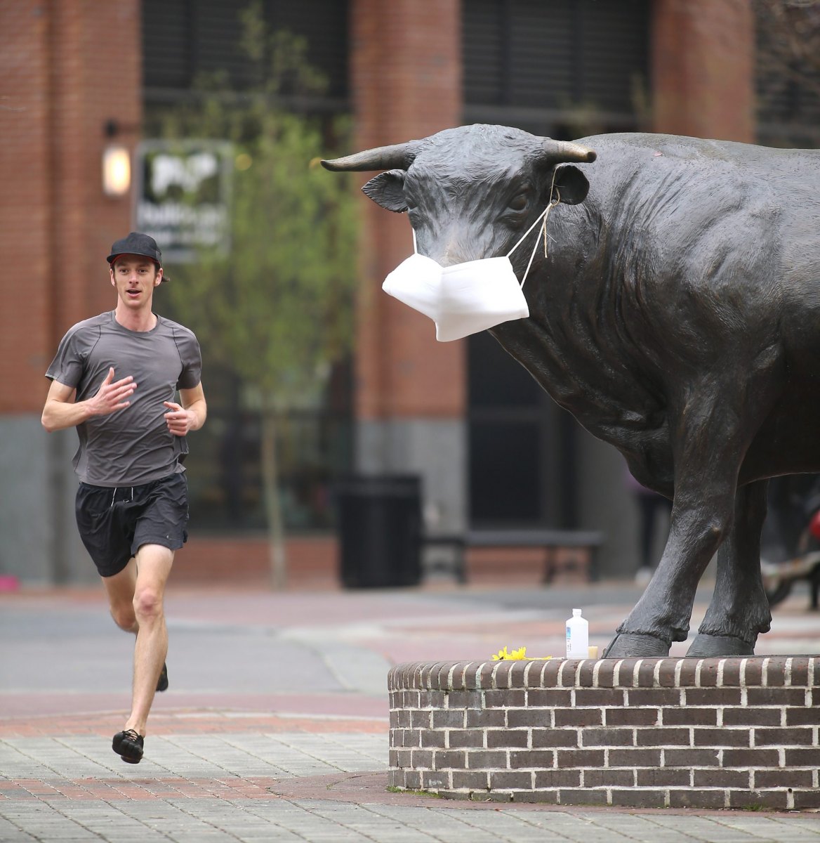 Paul Whittredge of Durham runs past Major the Bull in downtown Durham. Coronavirus day tripMarch 19, 2020. Durham, NC