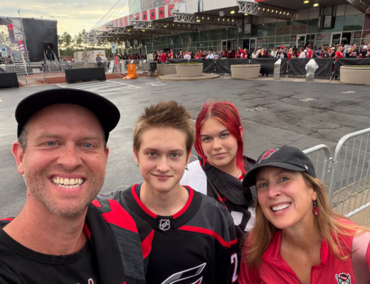 family of four smiles while standing in front of Lenovo Center ahead of Carolina Hurricane's game
