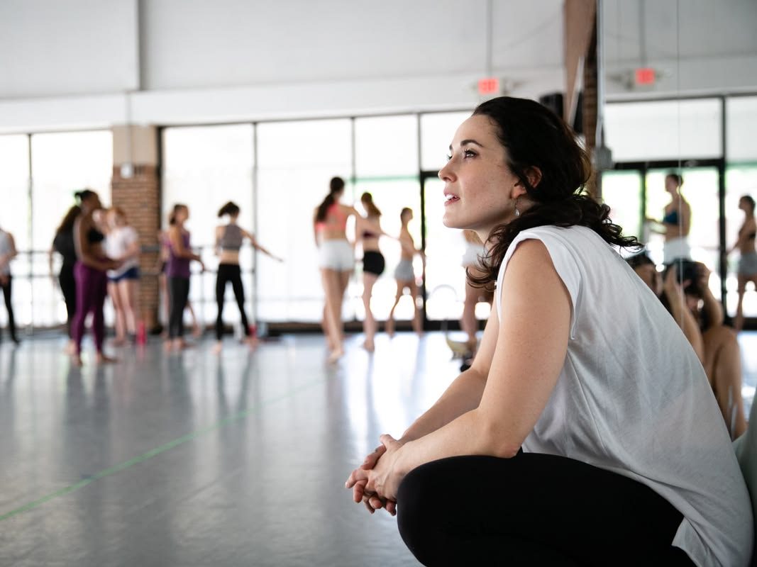 Dance instructor observes dancers from the front of the dance studio.