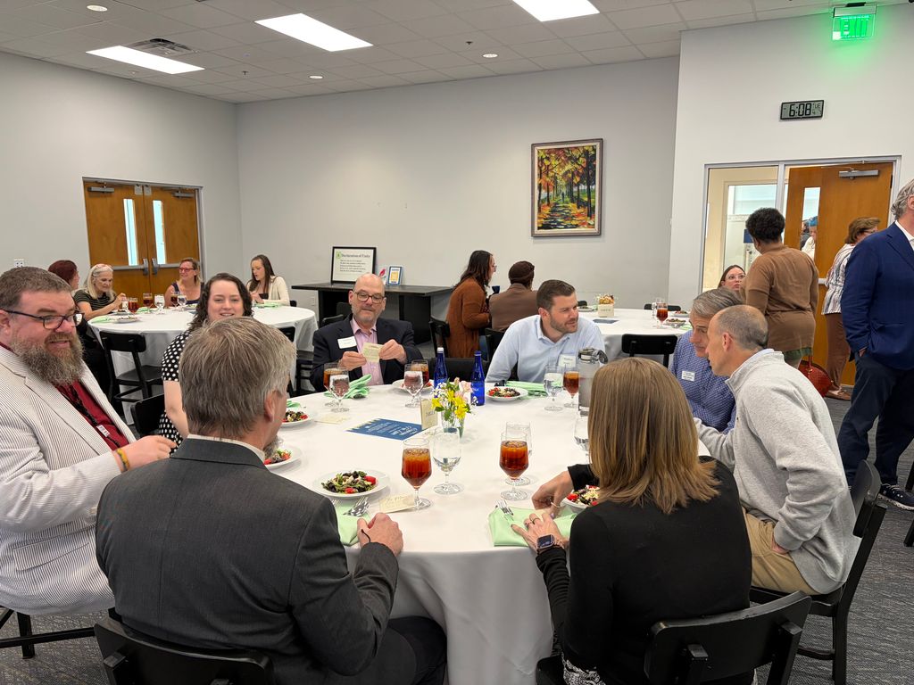 Group of people sitting at a round table while eating dinner