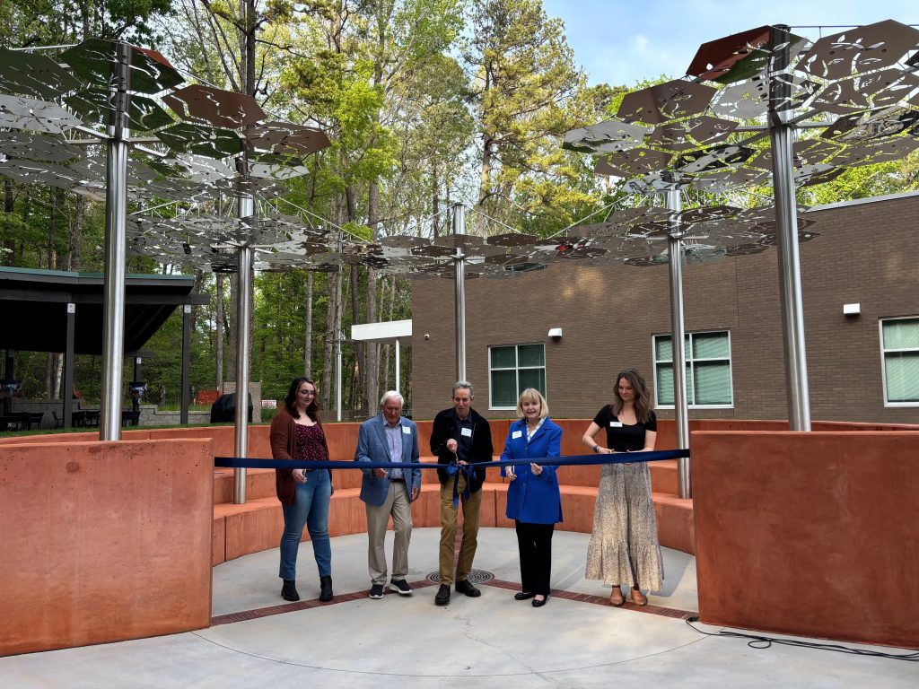 Five people pose for the ribbon cutting ceremony to open the women's courtyard